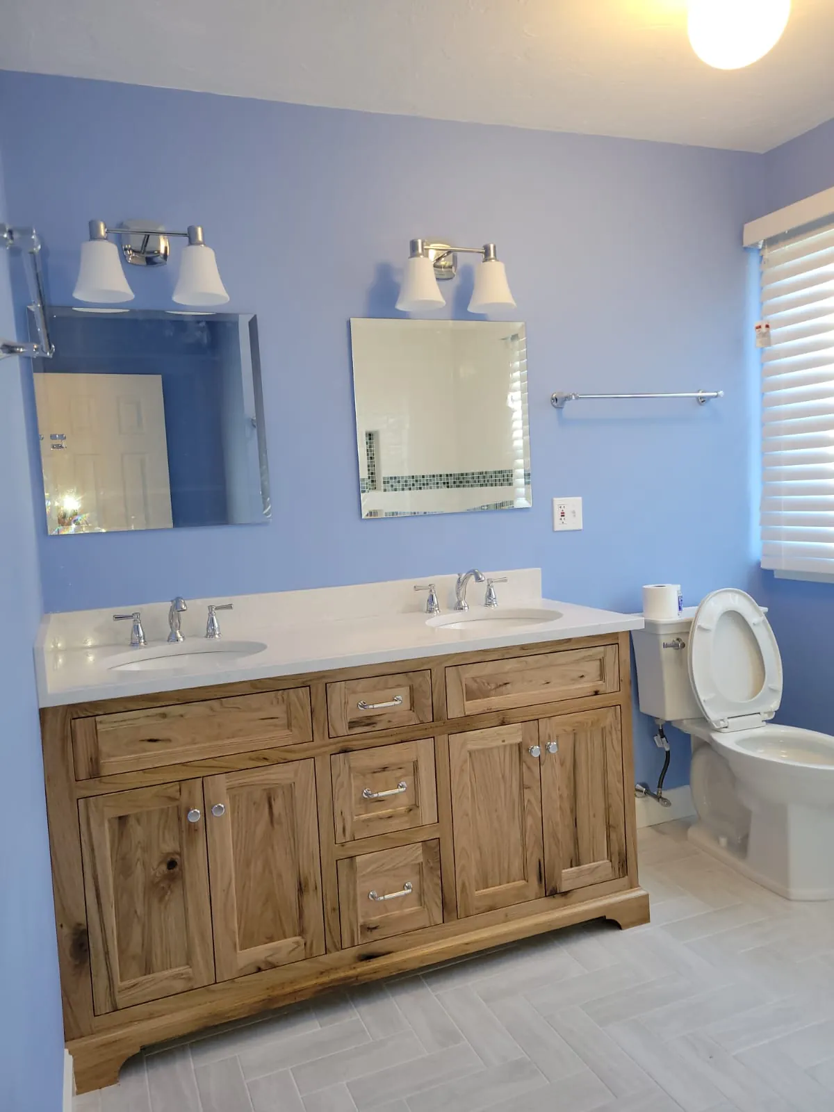 Bathroom remodel with a rustic wood double vanity, white quartz top, two mirrors and periwinkle blue walls