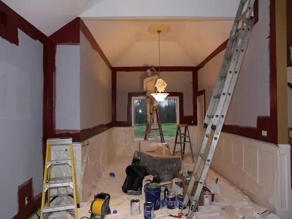 Dining room mid-renovation with ladders, wall repairs and wainscoting being prepared for paint