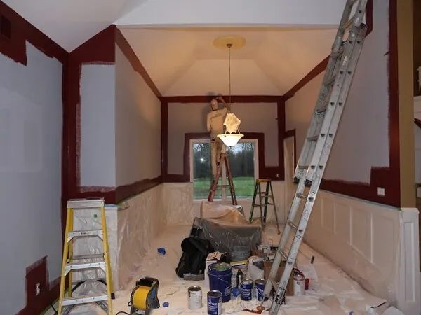 Dining room mid-renovation with ladders, wall repairs and wainscoting being prepared for paint