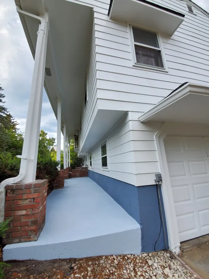 Painted foundation and walkway beside freshly painted white clapboard siding