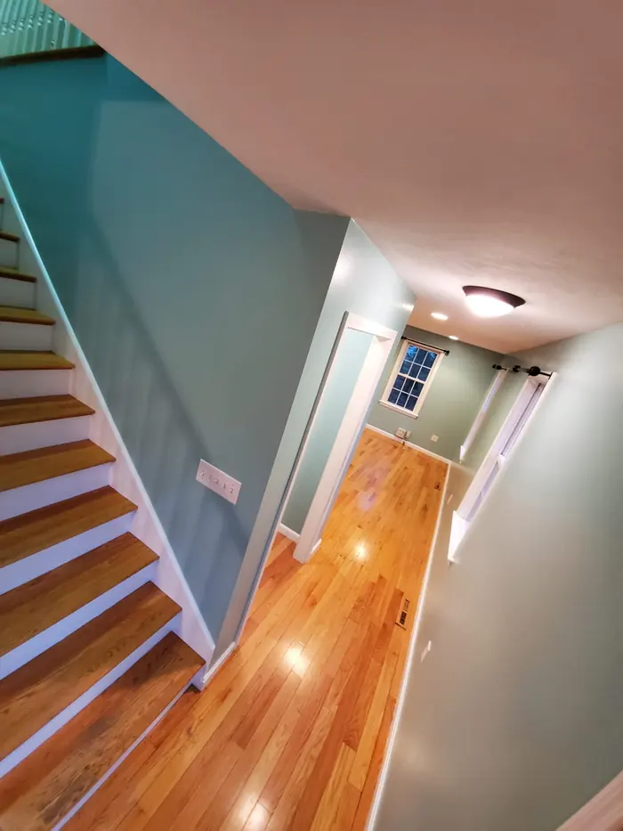 Stairwell with new hardwood treads, white risers and freshly painted teal and grey walls