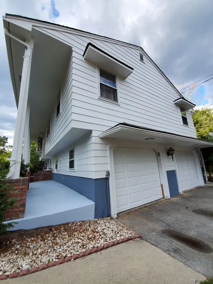 Garage side of a white split-level after exterior repainting with crisp white trim