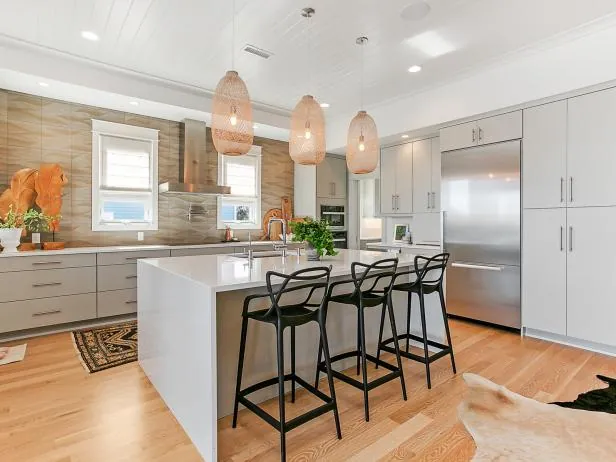Bright kitchen with white cabinets, island seating and wood range hood wall