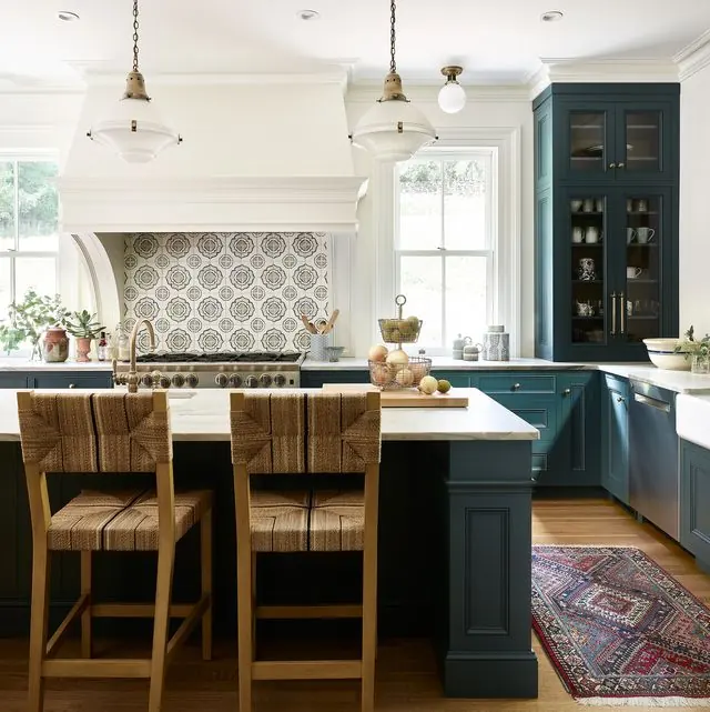Kitchen with teal cabinets, patterned tile backsplash and wood bar stools at the island