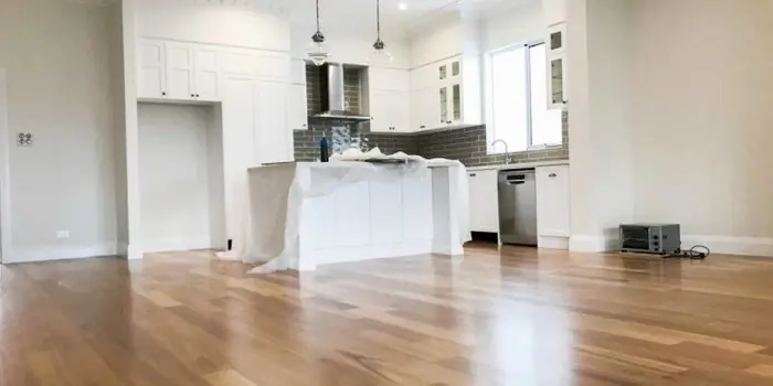 Open kitchen with new white cabinets and island under protective wrap during renovation