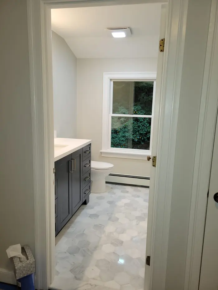 Marble hexagon floor tile and navy vanity seen through a bathroom doorway