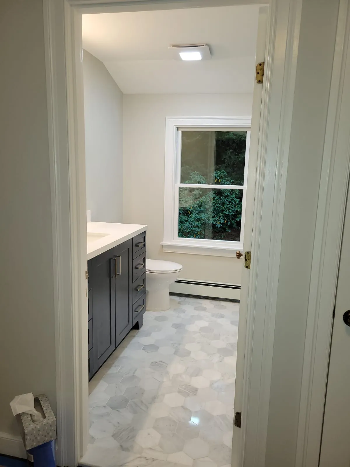 Marble hexagon floor tile and navy vanity seen through a bathroom doorway