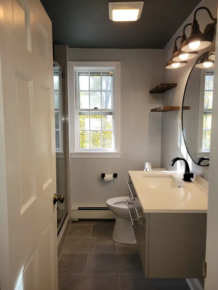 Modern bathroom with wall-hung grey vanity, black barn-style vanity light and slate-look floor tile