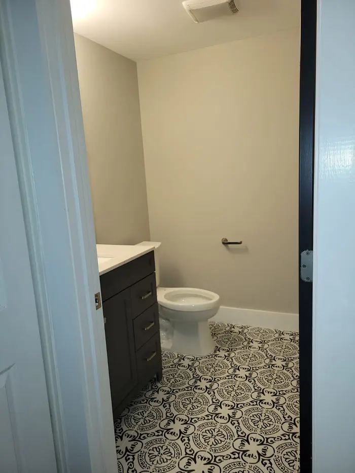 Black and white patterned cement-look floor tile in a small bathroom with navy vanity