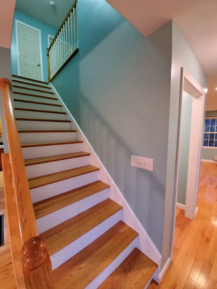 Looking up a painted stairwell with hardwood treads, white balusters and teal accent wall