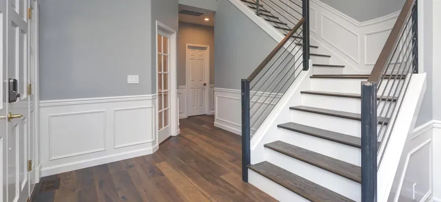 Entry hall with white wainscoting, smooth painted walls and stair with dark treads
