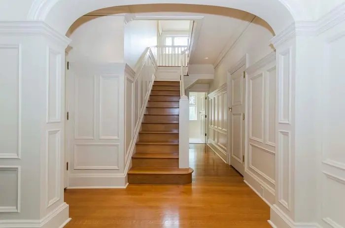 White paneled hallway and arched opening to a hardwood staircase