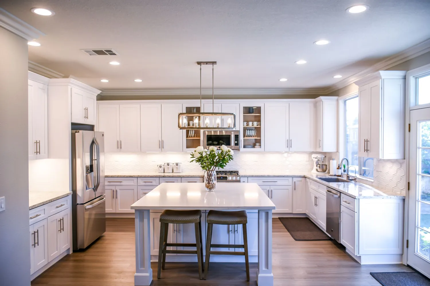 White shaker kitchen with large island, pendant lights and stainless appliances