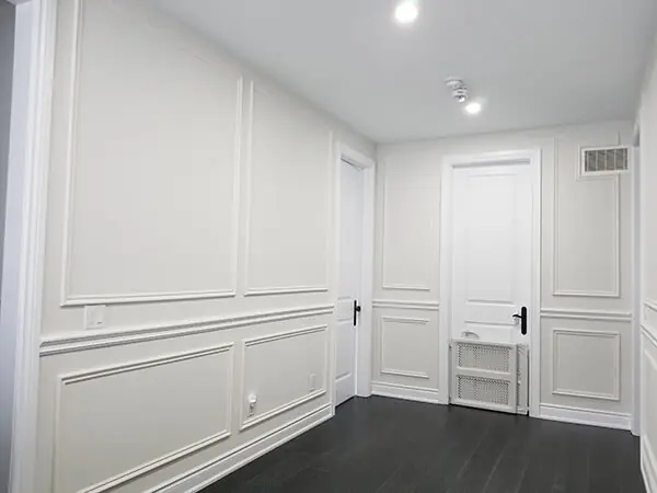 Hallway with smooth white walls, picture-frame wall moulding and dark wood-look floor